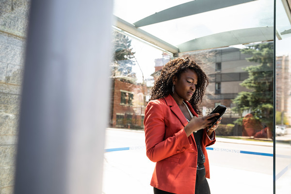 person checking their phone while standing in a bus stop