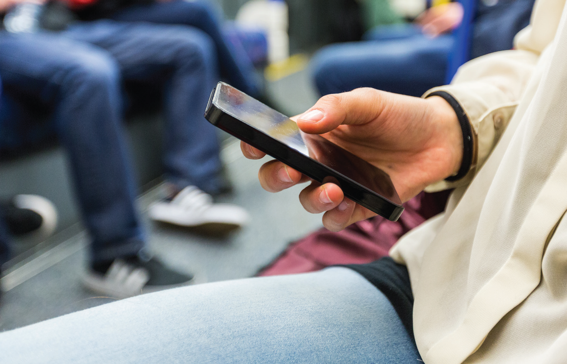 Hand holding a mobile phone on public transport